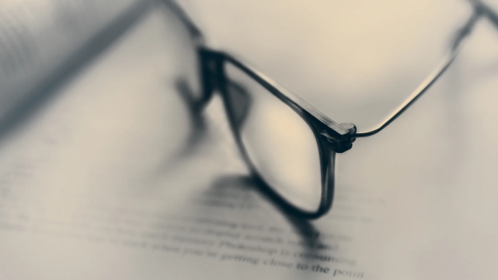 A pair of eyeglasses in close focus with a scene softly blurred behind the lenses